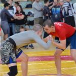 NoGi Grappling versenyszámban az elsőként pástra lépő versenyzőnek piros rashguard-ot kell viselnie